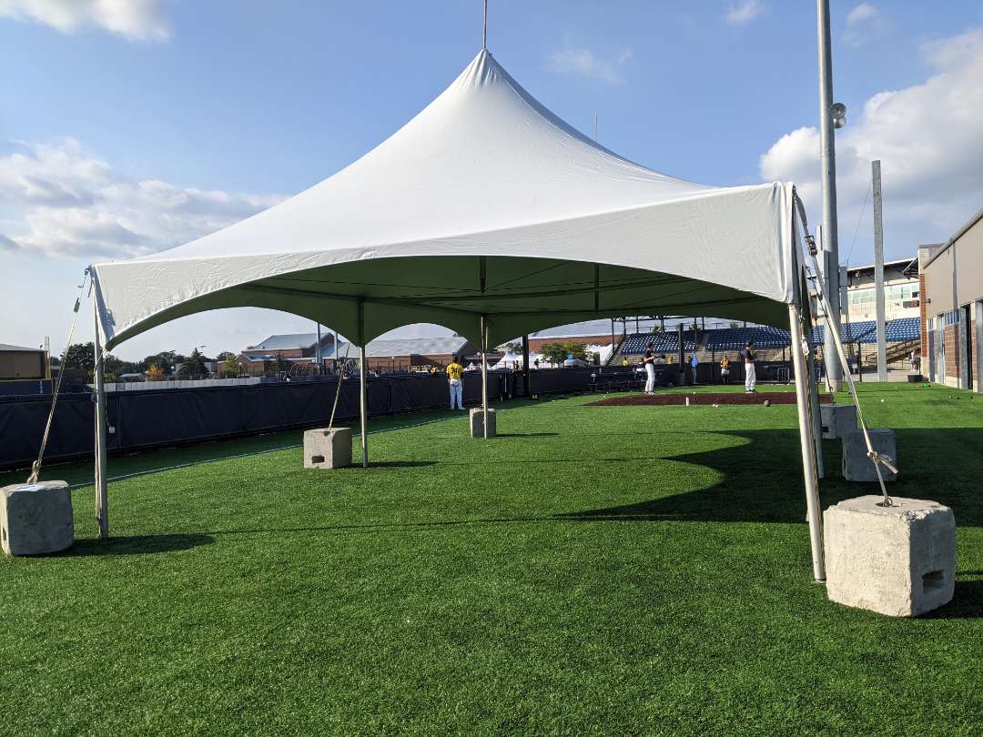 Large frame tent rental at University of Michigan festival event with weighted anchor blocks
